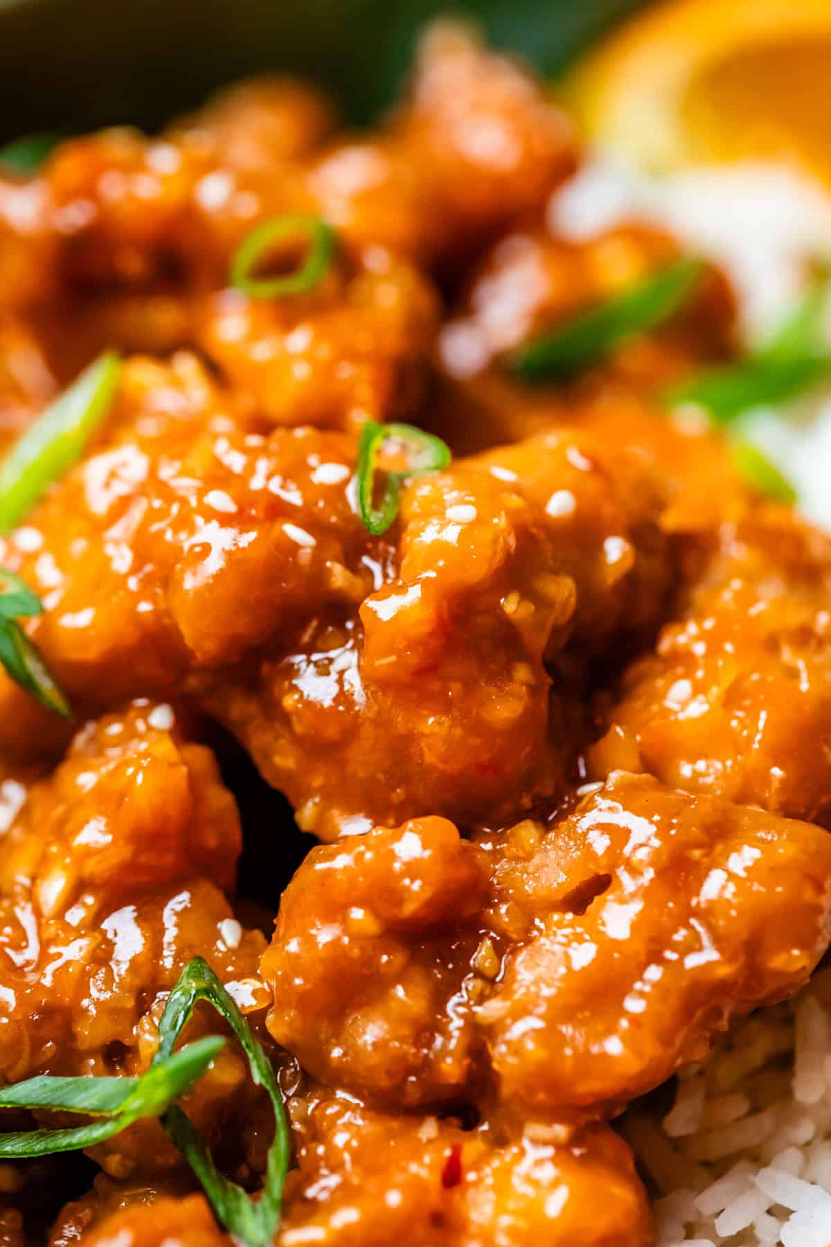 close up of crispy orange chicken with green onion garnish.