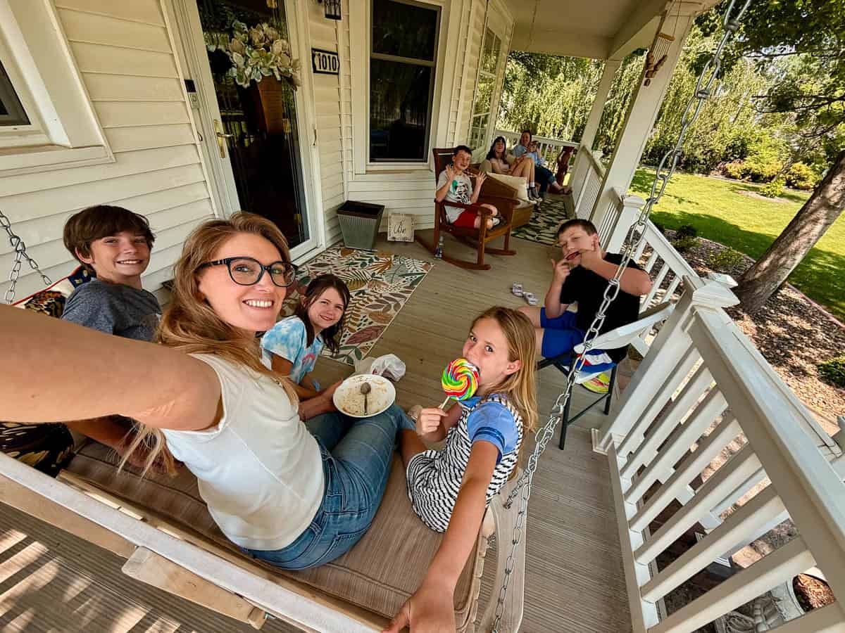 Family of mom and kids sitting on a porch in the summer. 