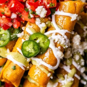 looking straight down at two flautas stacked on top of others, with lots of yummy garnishes.