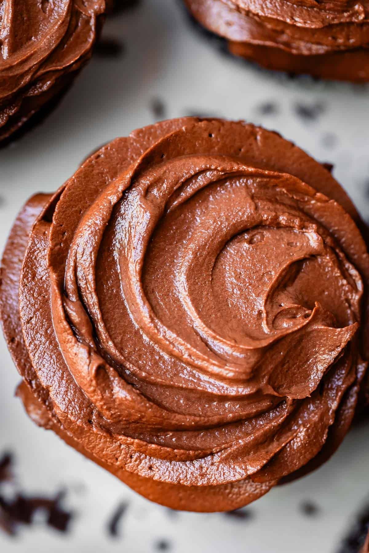 looking down at creamy chocolate buttercream frosting swirled on a cupcake.