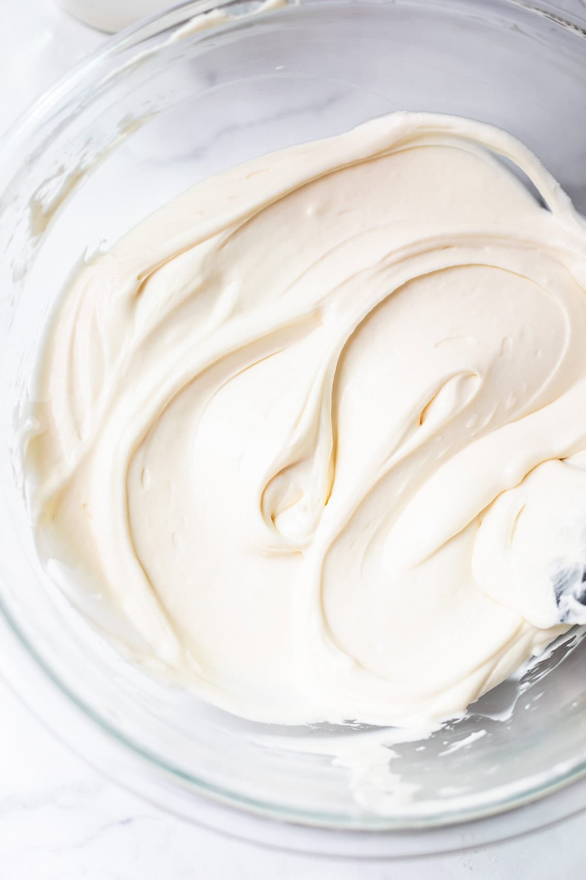 cream cheese frosting with the consistency of whipped cream in a glass bowl.