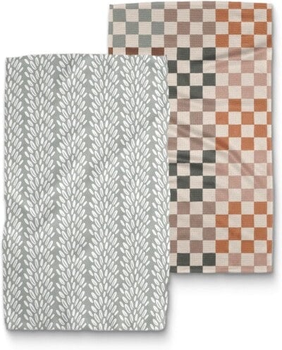 Two folded towels: one with a gray background and white leafy pattern, and the other with a checkerboard design in orange, gray, and beige tones.